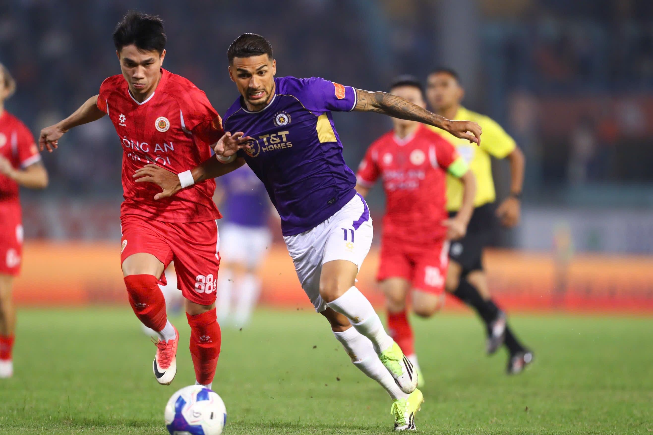 Hai cầu thủ Hà Nội FC và CAHN bám đuổi nhau trên sân cỏ, thể hiện sự kịch tính của trận derby