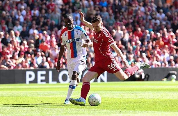 Hai cầu thủ Liverpool và Crystal Palace tranh chấp bóng quyết liệt trên sân cỏ, thể hiện động lực thi đấu của hai đội.
