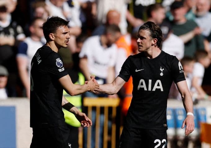 Hai cầu thủ Tottenham bắt tay trên sân, thể hiện tinh thần đồng đội trong cuộc đua trụ hạng Ngoại hạng Anh.