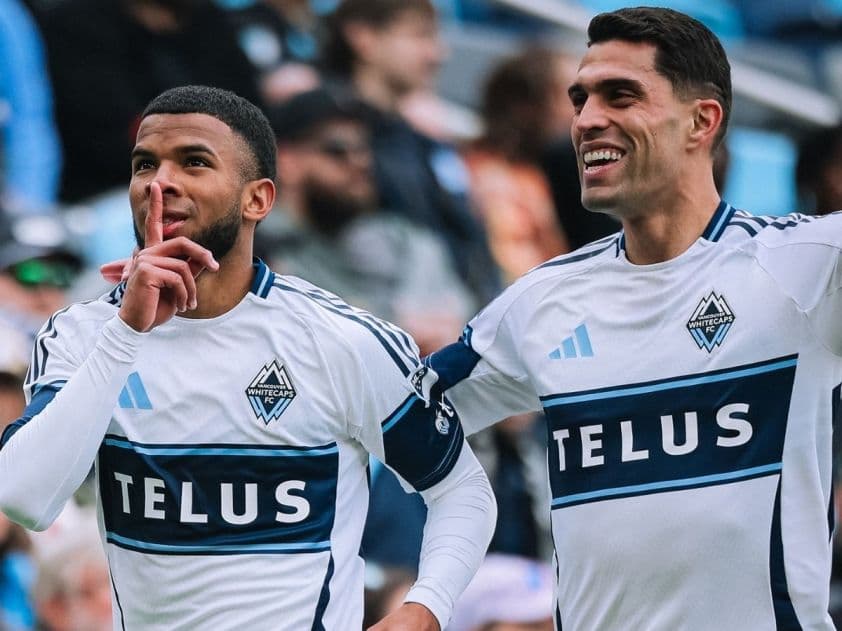 Hai cầu thủ Vancouver Whitecaps ăn mừng trên sân trong trận đấu MLS
