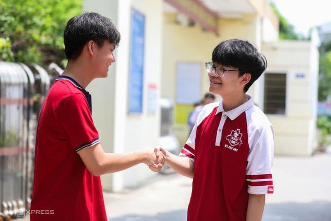 Hai học sinh lớp 10 Hà Nội bắt tay và mỉm cười trong khuôn viên trường học.
