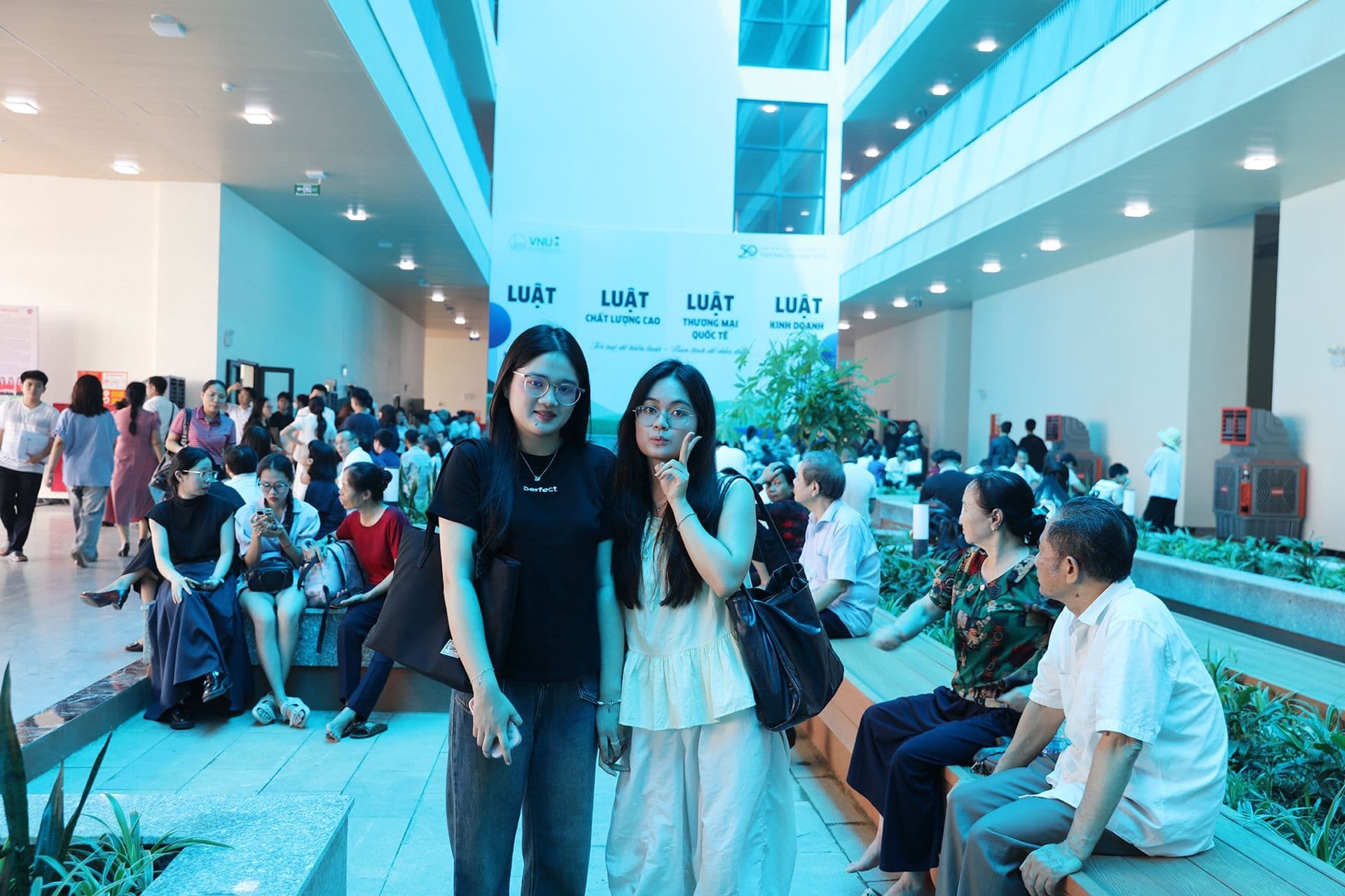 Hai nữ sinh viên trong sảnh trường đại học hiện đại, thể hiện môi trường học tập mới