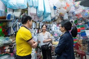 Hai người đang trò chuyện với một chủ cửa hàng, thể hiện các giao dịch và tương tác trong đời sống thường ngày.
