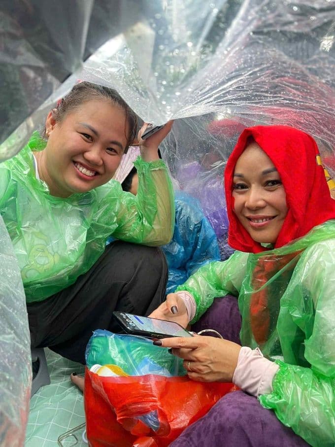 Hai người bạn của chị Bùi Thị Lý mặc áo mưa, trú dưới bạt, kiên nhẫn chờ đợi buổi tổng duyệt diễu binh tại Hà Nội.