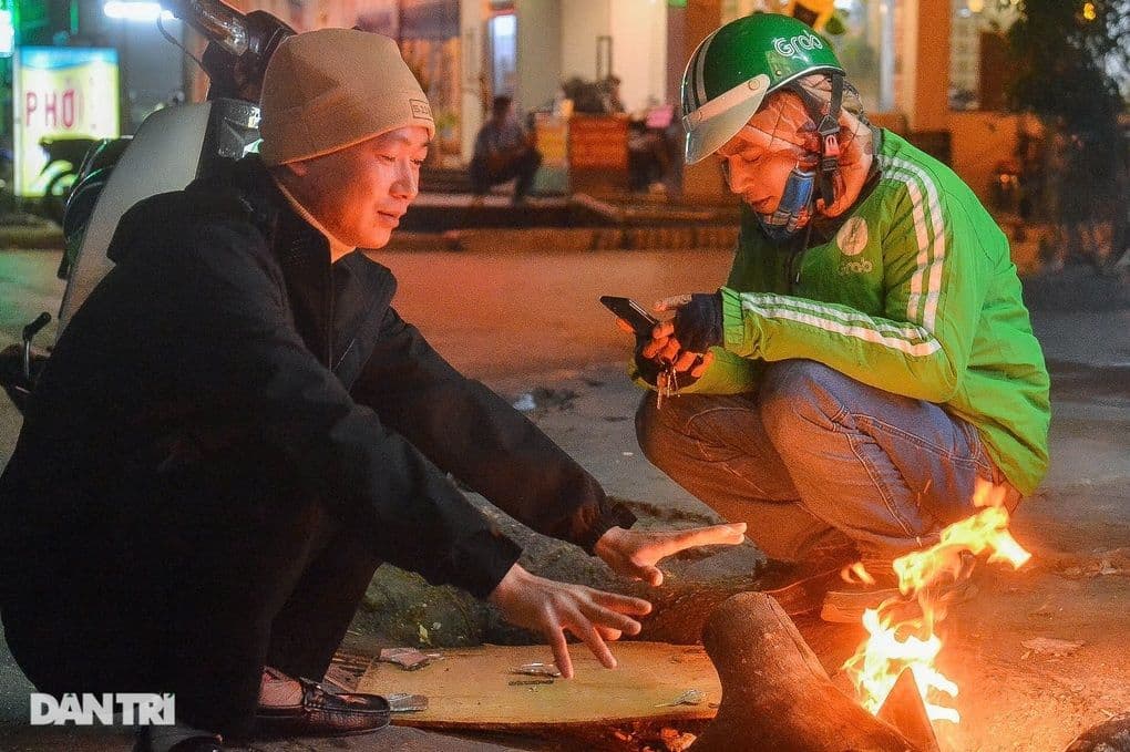 Hai người đàn ông sưởi ấm bên lửa nhỏ trong đêm đông lạnh giá ở miền Bắc Việt Nam.