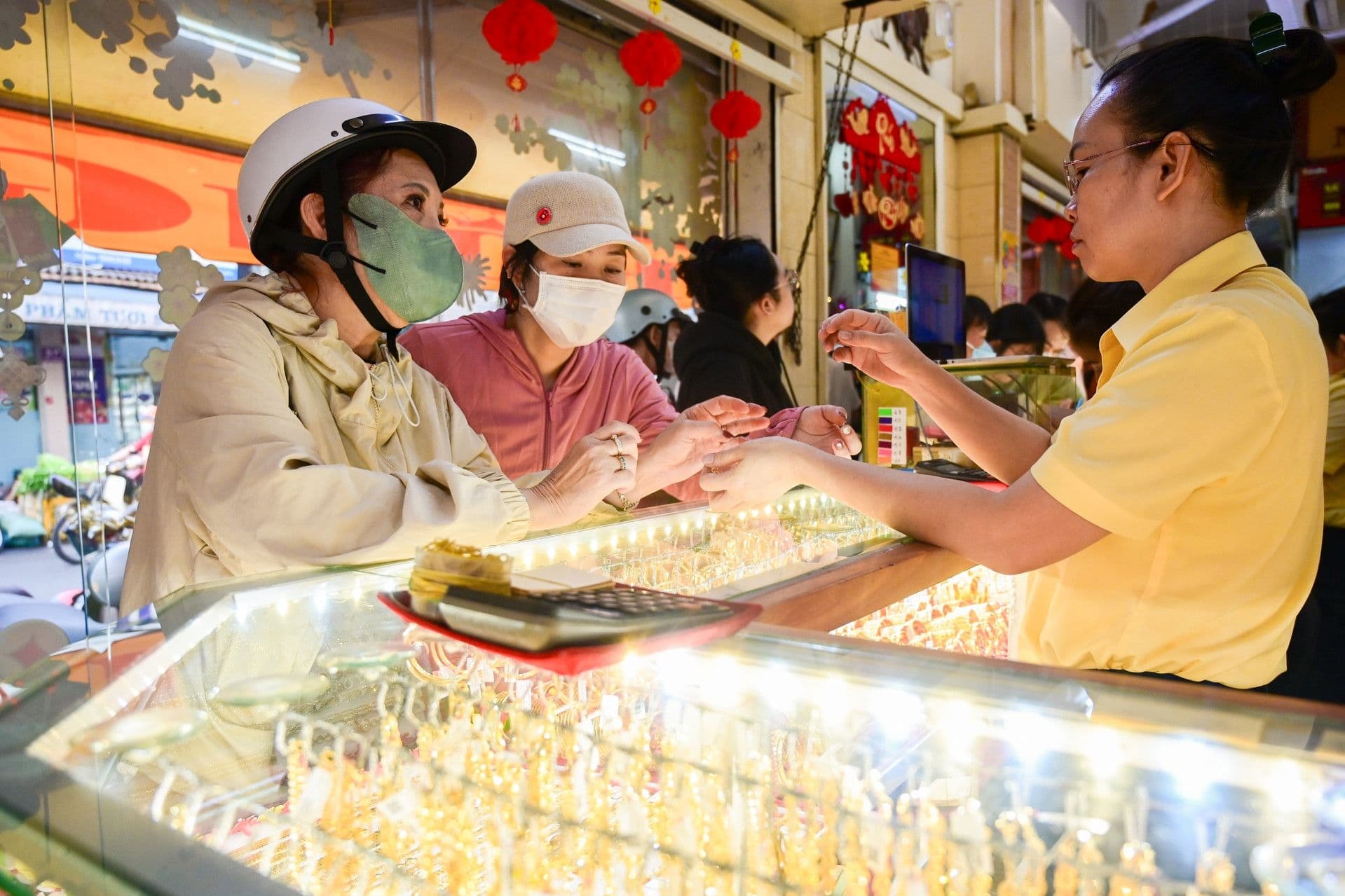 Hai người phụ nữ đang giao dịch mua vàng tại quầy, phản ánh nhu cầu và rủi ro của người mua trên thị trường vàng SJC.