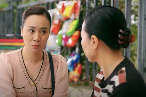 Hai người phụ nữ trao đổi với vẻ mặt nghiêm trọng, thể hiện sự giằng xé lương tâm và khó khăn do sáp nhập.