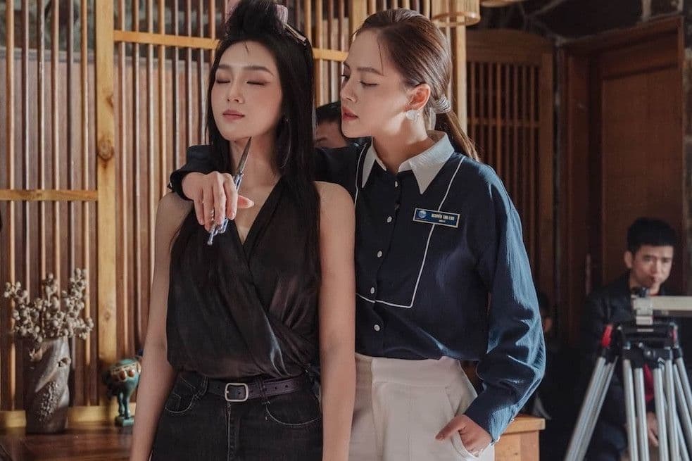 Hai người phụ nữ trong cảnh phim 'Lửa Trắng' với kéo kề cổ, thể hiện sự căng thẳng và nguy hiểm trong thế giới ngầm