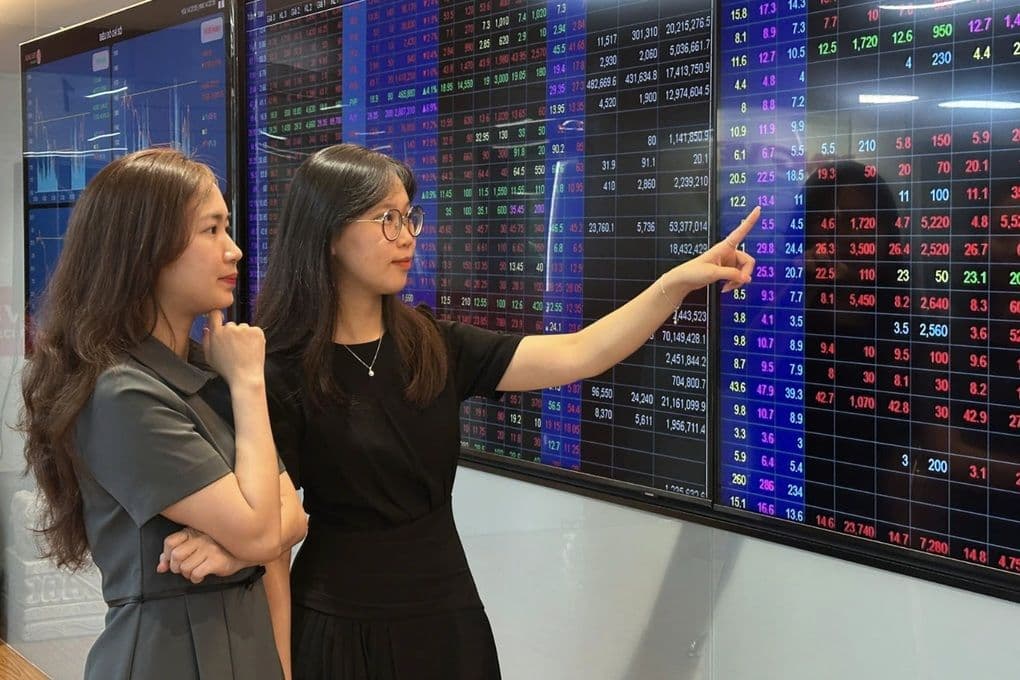 Hai nhà đầu tư nữ đang phân tích dữ liệu trên màn hình chứng khoán, thể hiện sự biến động của thị trường cổ phiếu Việt Nam.