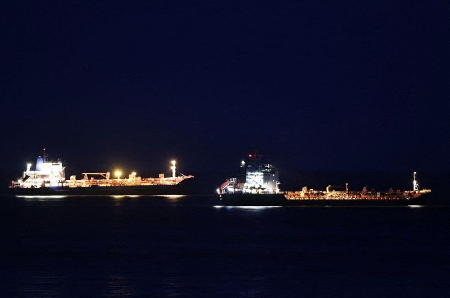 Hai tàu chở dầu di chuyển trên biển vào ban đêm, tượng trưng cho dòng chảy năng lượng toàn cầu và những rủi ro địa chính trị.