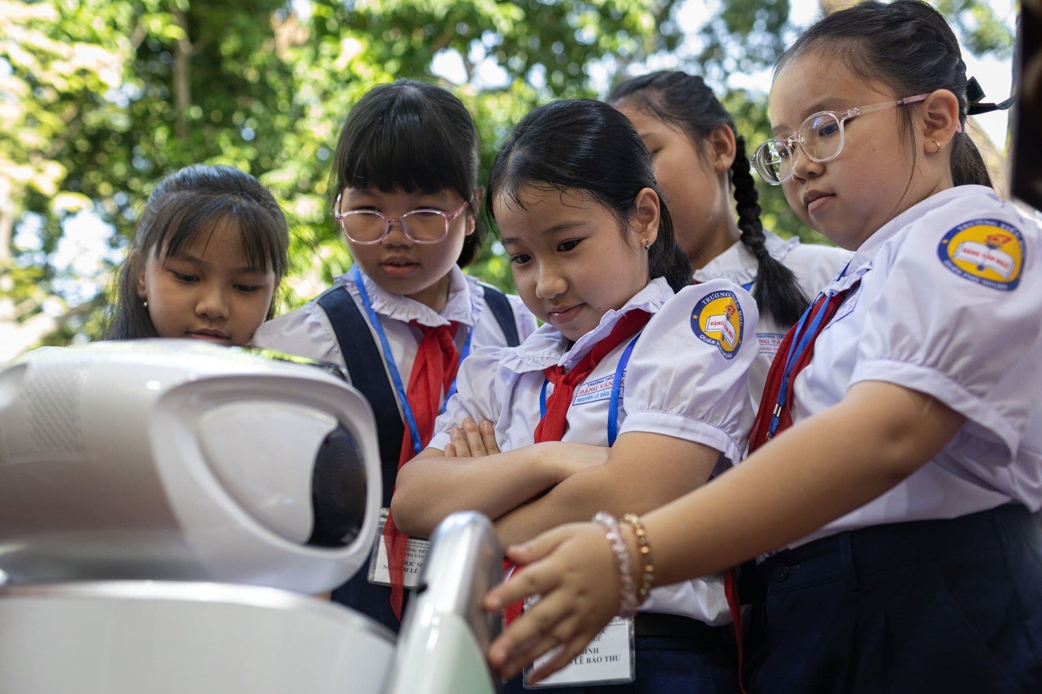 Học sinh tiểu học tương tác với robot, thể hiện đổi mới giáo dục và công nghệ.