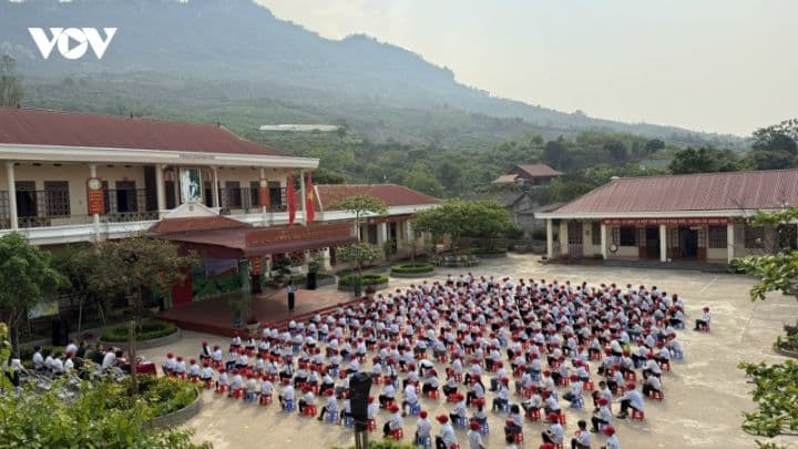 Học sinh tập trung tại sân trường trong buổi lễ chào cờ, tượng trưng cho quy mô lớn của các trường học sau sáp nhập.