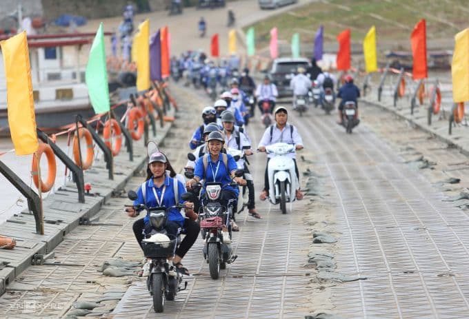 Học sinh và người dân đi xe máy qua cầu phao Phong Châu, thể hiện vai trò giữ nhịp huyết mạch của bộ đội công binh.