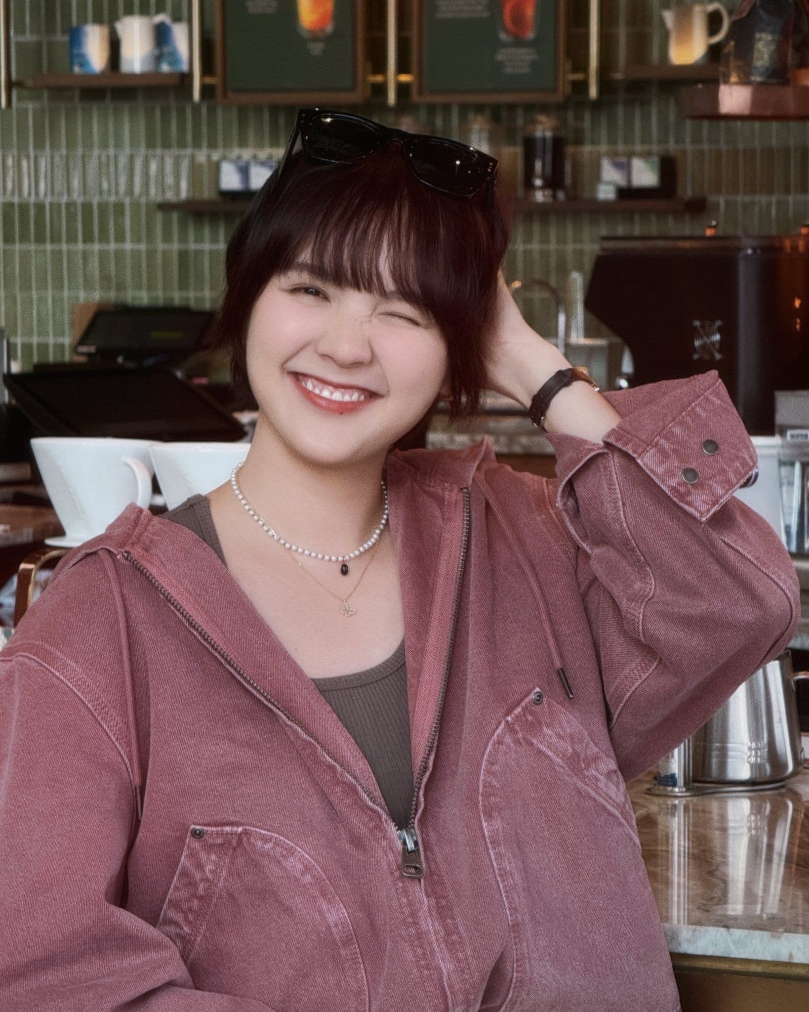 Hải Tú mỉm cười rạng rỡ trong quán cà phê, thể hiện sự tự tin và bình thản giữa những ồn ào.