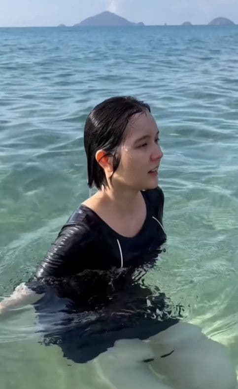 Hải Tú trong trang phục bơi ở biển, đại diện cho hình ảnh người nổi tiếng dưới sự chú ý của công chúng.