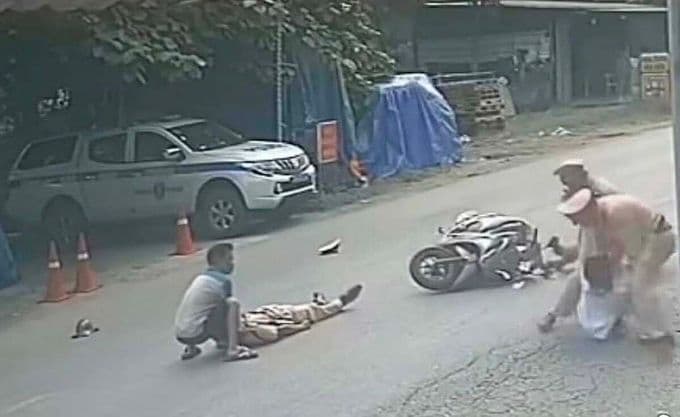 Hiện trường vụ cảnh sát giao thông bị tông xe khi đang làm nhiệm vụ, một sĩ quan nằm trên đường cạnh xe máy và xe cảnh sát.