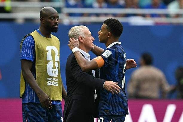 HLV Didier Deschamps và Kylian Mbappe ôm nhau, thể hiện sự giải tỏa và tinh thần thể thao sau trận đấu căng thẳng.