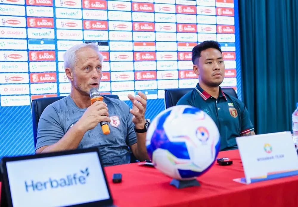 HLV Jorn Andersen và cầu thủ Myanmar tại buổi họp báo, tượng trưng cho giai đoạn chuyển giao của bóng đá Myanmar.
