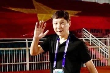 HLV Kim Sang-sik vẫy tay chào người hâm mộ với lá cờ Việt Nam phía sau, biểu tượng cho việc hồi sinh niềm tin và tạo đà cho bóng đá trẻ.