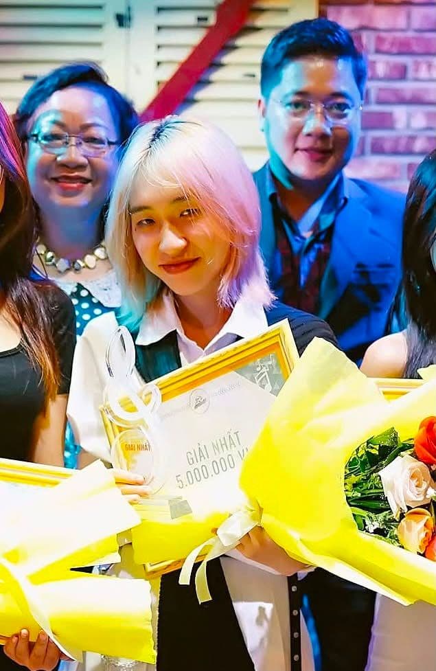 Hồng Yên với mái tóc vàng hồng, tươi cười nhận giải thưởng âm nhạc, đại diện cho thành công từ sự chân thật.
