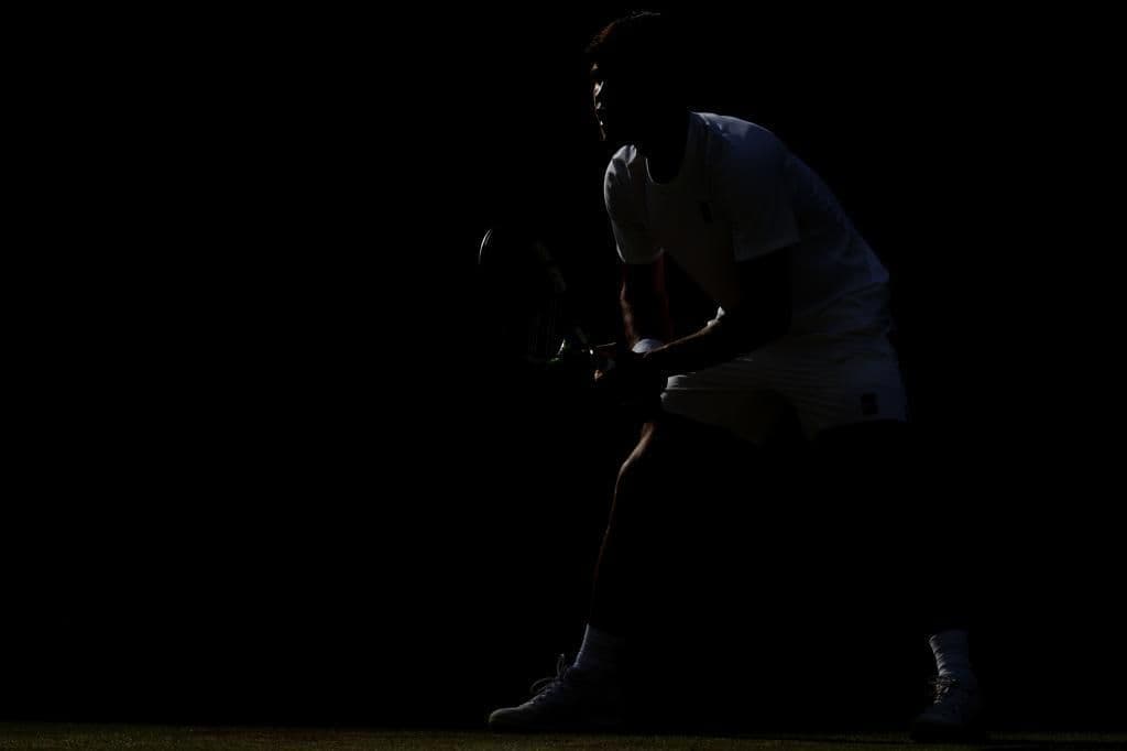 Hình ảnh bóng của một tay vợt tennis trên sân cỏ Wimbledon, tượng trưng cho sự khởi đầu trận chung kết lịch sử.