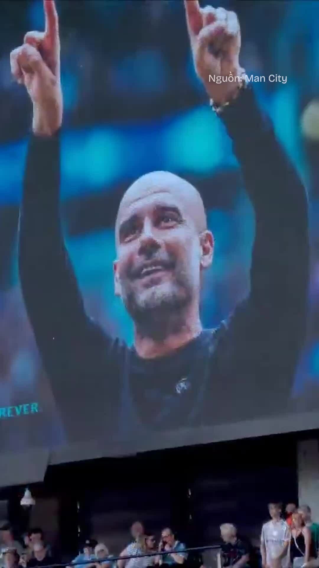 Hình ảnh Pep Guardiola trên màn hình lớn với hai tay giơ cao, tượng trưng cho di sản vĩ đại và lời tạm biệt của ông tại Manchester City.