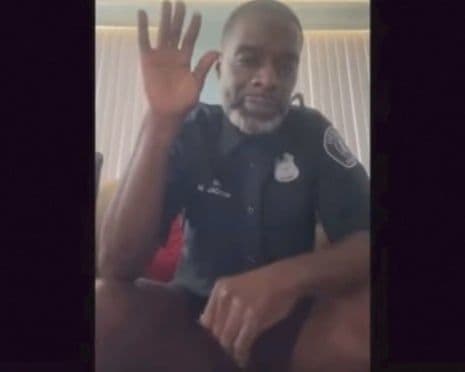 Hình ảnh sĩ quan cảnh sát Matthew Jackson trong phiên tòa Zoom, mặc áo đồng phục nhưng không mặc quần, giơ tay chào, minh họa sự cố 'vụ án quần'.