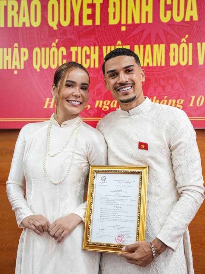 Đỗ Hoàng Hên và vợ tự hào cầm quyết định nhập quốc tịch Việt Nam trong trang phục áo dài truyền thống.