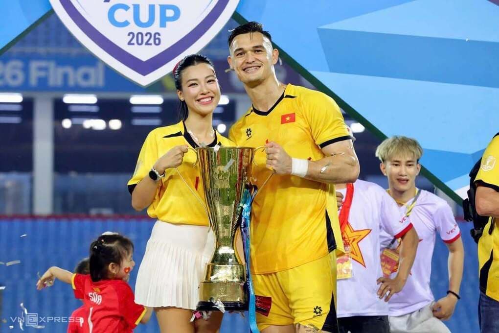 Hoàng Oanh và Patrik Lê Giang hạnh phúc bên cúp vô địch ASEAN Cup 2026, cả hai mặc áo đấu vàng.