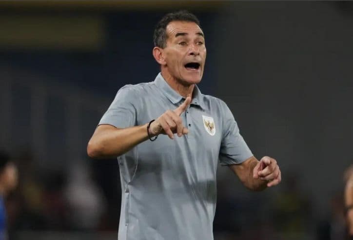 Huấn luyện viên bóng đá đang chỉ đạo trên sân, thể hiện sự quyết tâm hoặc chiến thuật.