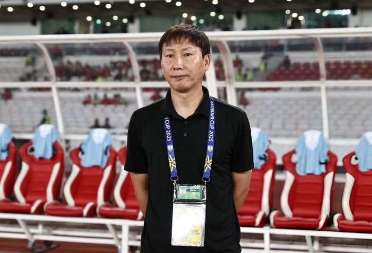 Huấn luyện viên bóng đá đứng trên sân, suy tư về chiến thuật hoặc kết quả trận đấu.