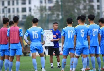 Huấn luyện viên hướng dẫn chiến thuật cho các cầu thủ trẻ, thể hiện sự chuẩn bị cho trận đấu