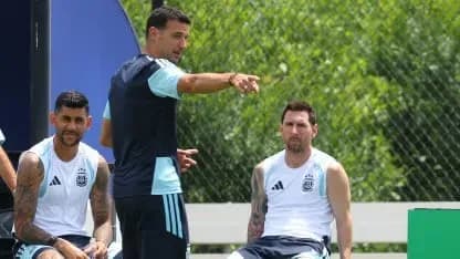 Huấn luyện viên Lionel Scaloni của Argentina đang chỉ đạo trên sân tập, với Lionel Messi và một cầu thủ khác ngồi cạnh.