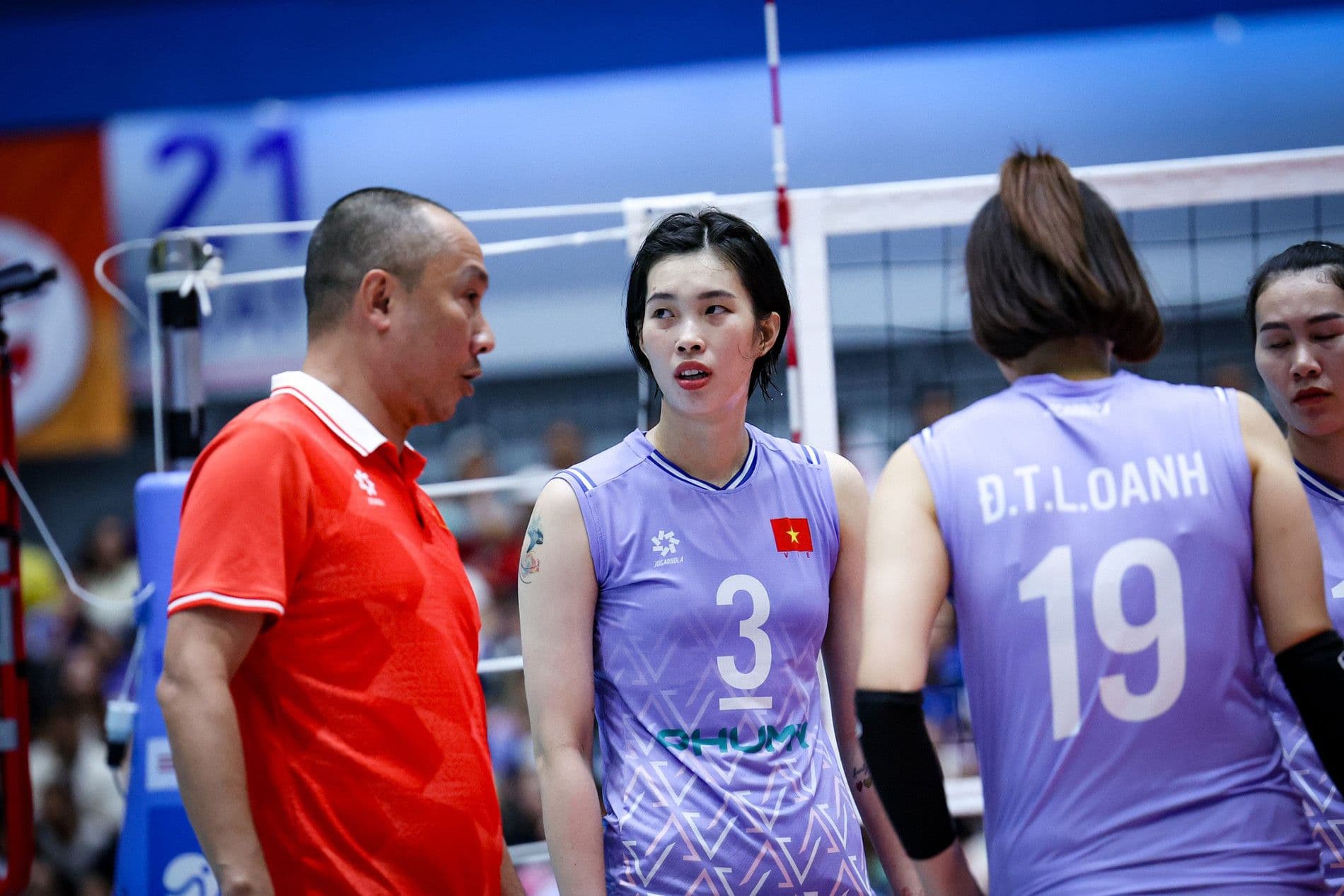 Huấn luyện viên và vận động viên bóng chuyền nữ Việt Nam thảo luận chiến thuật trên sân.