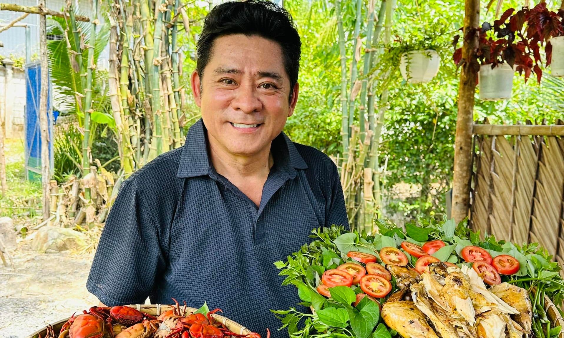 Huỳnh Anh Tuấn tươi cười bên mâm thức ăn dân dã trong khu vườn của mình, thể hiện cuộc sống điền viên.