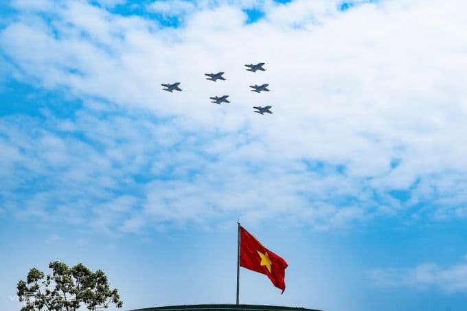 Đội hình tiêm kích Su-30MK2 bay qua Quảng trường Ba Đình cùng lá cờ Tổ quốc, thể hiện niềm tự hào dân tộc.