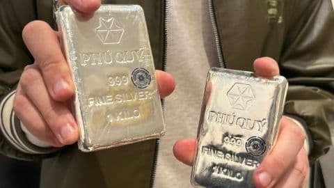 Đôi tay đang cầm hai thỏi bạc Phú Quý 999.9, tượng trưng cho giao dịch và đầu tư bạc.