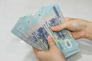 Đôi tay đang đếm những tờ tiền mệnh giá 500.000 đồng của Việt Nam, tượng trưng cho các giao dịch tài chính và tiện ích kinh tế.