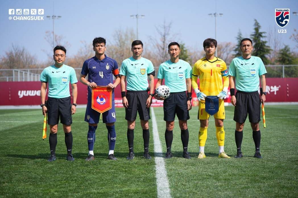 Đội trưởng U23 Việt Nam và U23 Thái Lan cùng trọng tài trước trận đấu, tượng trưng cho sự chuẩn bị và tầm nhìn phát triển bóng đá.