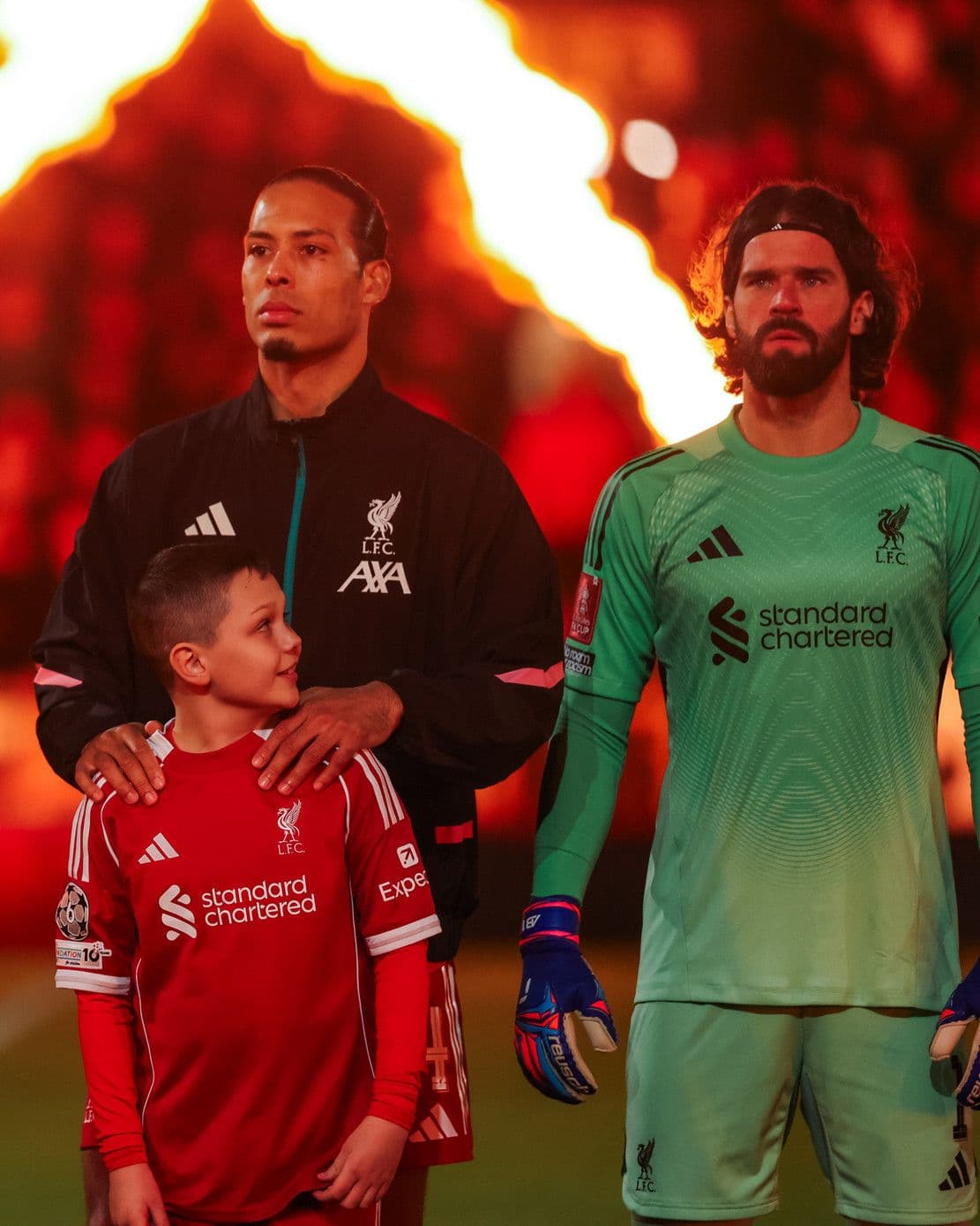 Đội trưởng Virgil van Dijk và thủ môn Alisson Becker của Liverpool cùng một cậu bé, thể hiện tinh thần chiến đấu mạnh mẽ.