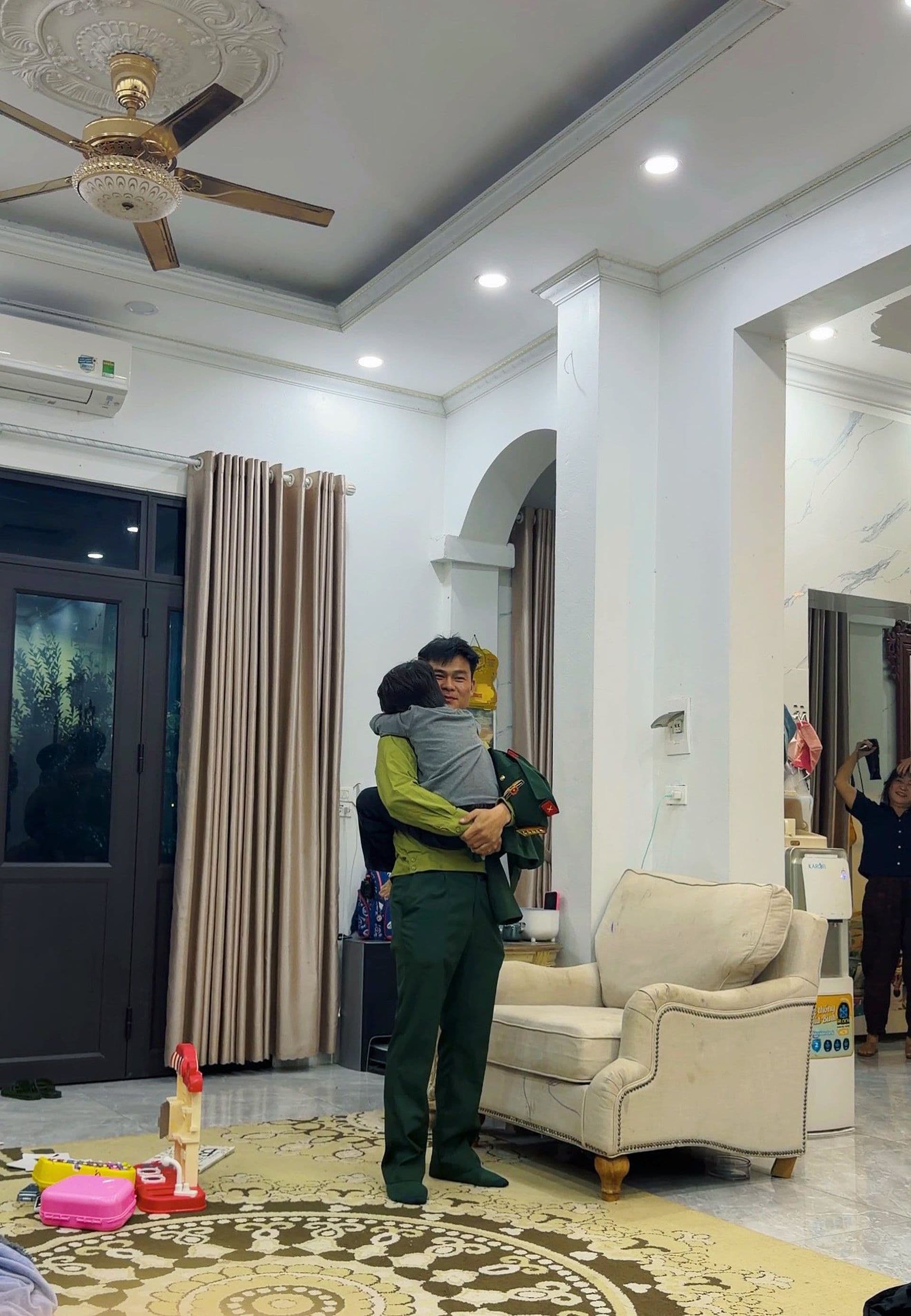 Đại úy Văn Cương ân cần bế bé Bo, thể hiện tình cảm gắn kết và mô hình gia đình hiện đại.