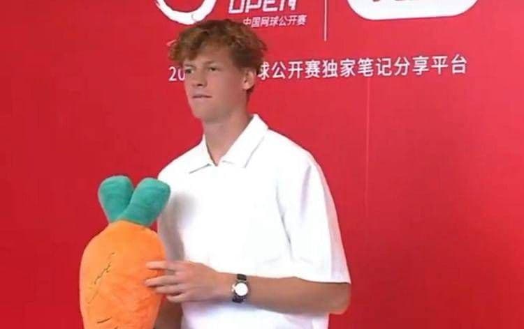 Jannik Sinner tươi cười cầm củ cà rốt nhồi bông khổng lồ tại sự kiện ở Bắc Kinh.