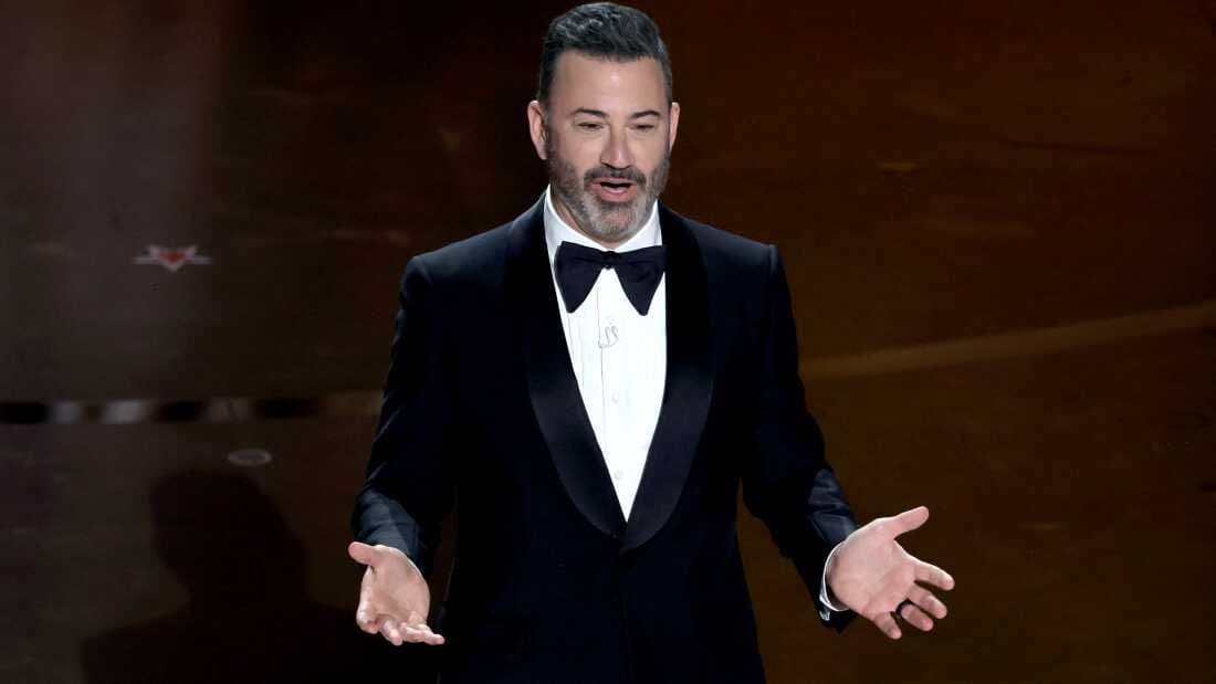 Jimmy Kimmel trong bộ tuxedo trên sân khấu, tượng trưng cho vai trò của anh là người dẫn chương trình Oscar và biểu tượng hài đêm khuya.