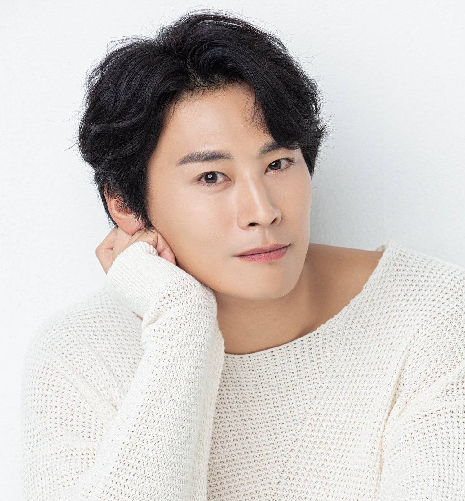 Jung Eun Woo với vẻ mặt trầm tư, mặc áo len trắng, tựa cằm vào tay, thể hiện sự nội tâm và nỗi buồn sâu kín.