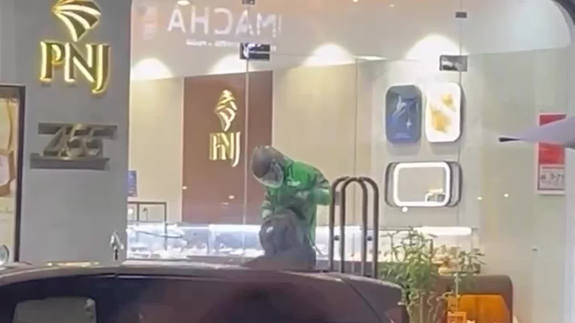 Kẻ cướp mặc áo xe ôm công nghệ màu xanh đang thực hiện hành vi cướp tại tiệm vàng PNJ Đà Nẵng.