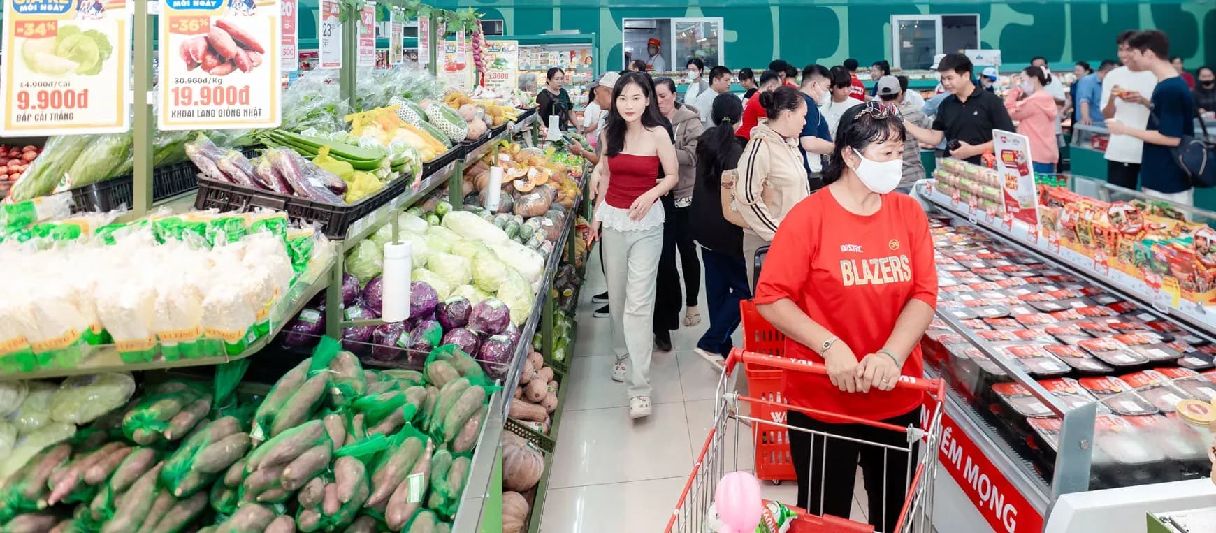 Khách hàng nữ mua sắm thực phẩm tươi sống và hàng tiêu dùng tại siêu thị.