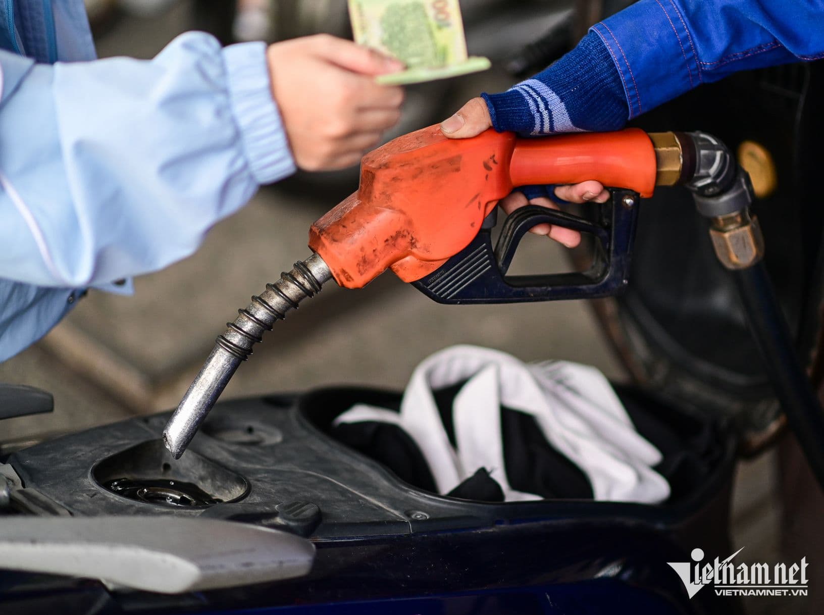 Khách hàng trả tiền mua xăng cho xe máy tại cây xăng, minh họa thực tế giá xăng người dân phải chi trả.