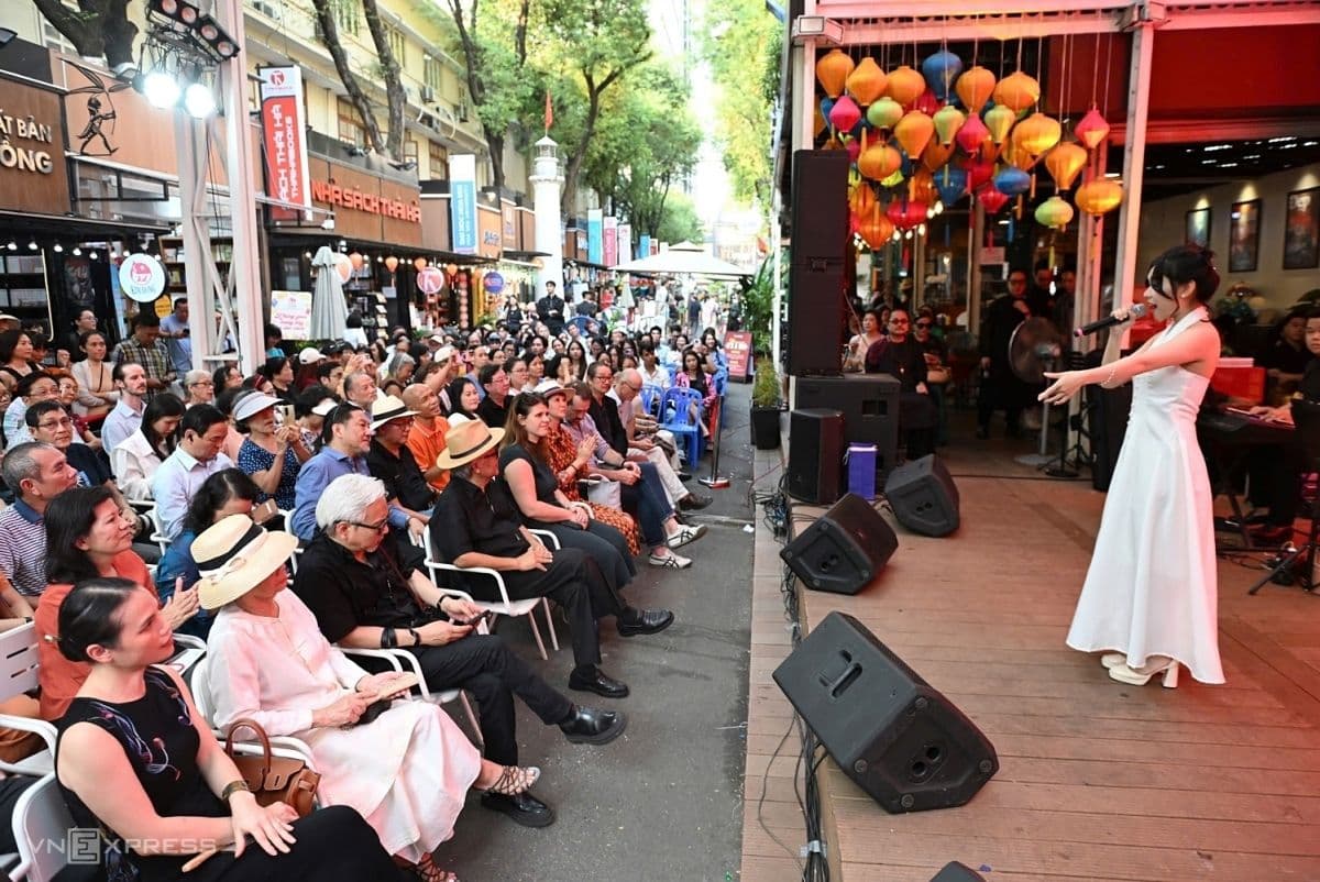 Khán giả đông đảo tại một đêm nhạc Trịnh Công Sơn ngoài trời, với một nữ ca sĩ mặc áo dài trắng đang biểu diễn trên sân khấu.