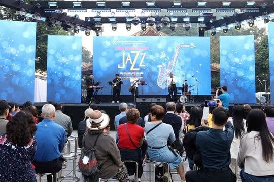 Khán giả thưởng thức chương trình nhạc Jazz ngoài trời tại không gian công cộng đô thị, thể hiện sự giao thoa của nhạc xuân và đời sống thành phố.