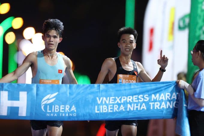 Khoảnh khắc Vòng Vành Long và Lê Đình Tường nắm tay cán đích, biểu tượng tinh thần đoàn kết tại VnExpress Marathon Nha Trang.